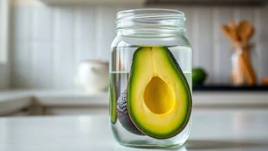 Como Conservar Abacate Sem Ficar Preto: Truque Da Água 45 Metade de abacate com polpa perfeitamente verde e fresca, submersa em água cristalina dentro de um pote de vidro, demonstrando o método de conservação.