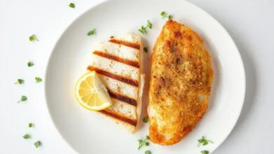 Merluza E Tilápia: Qual Escolher? Sabor, Textura E Preço 63 Dois filés de peixe lado a lado em um prato de fundo branco, mostrando a textura macia da merluza e a crocância da empanada da tilápia.