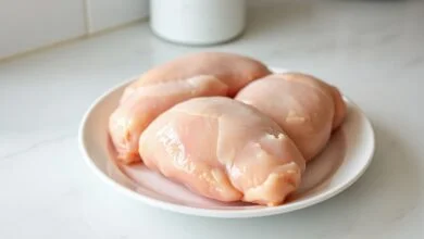 Descongelar Frango No Micro-ondas Em 5 Minutos — Sem Cozinhar 55 Peitos de frango macios e uniformemente descongelados, prontos para o preparo, em um prato de micro-ondas.