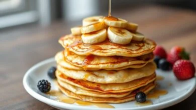 Panqueca De Banana E Ovo: Apenas 2 Ingredientes E Sem Farinha 58 Pilha de panquecas douradas e finas, com textura de crepe, decoradas com fatias de banana caramelizada e um fio de mel.