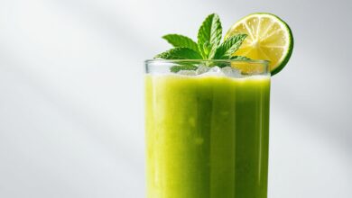 Suco Verde Simples E Prático: Receita Definitiva Em 5 Minutos 42 Um copo alto de vidro transparente contendo o suco verde vibrante e homogêneo, decorado com folhas de hortelã fresca e fatias de limão na borda.